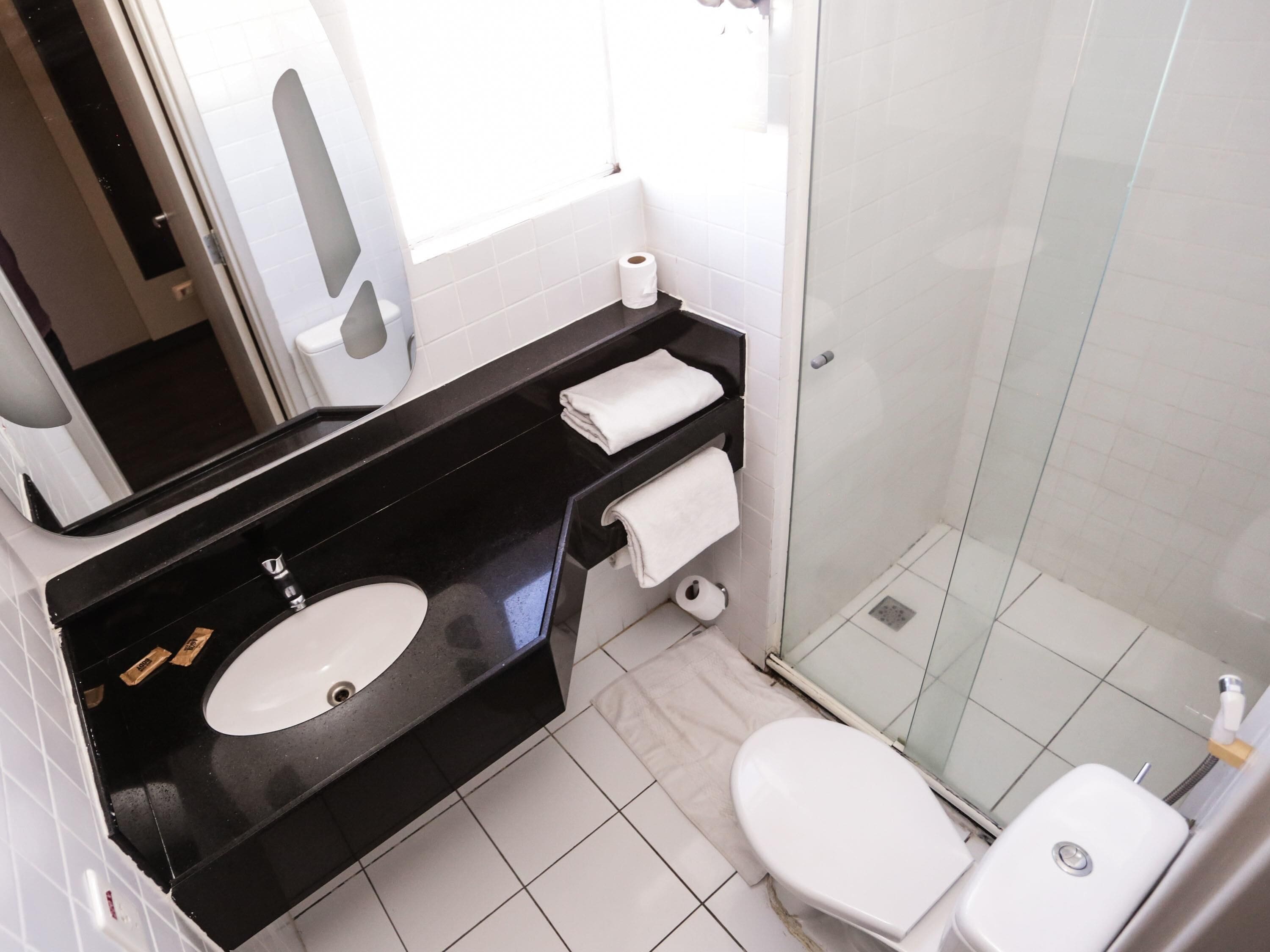 A bathroom with a black countertop, white sink, and toilet.