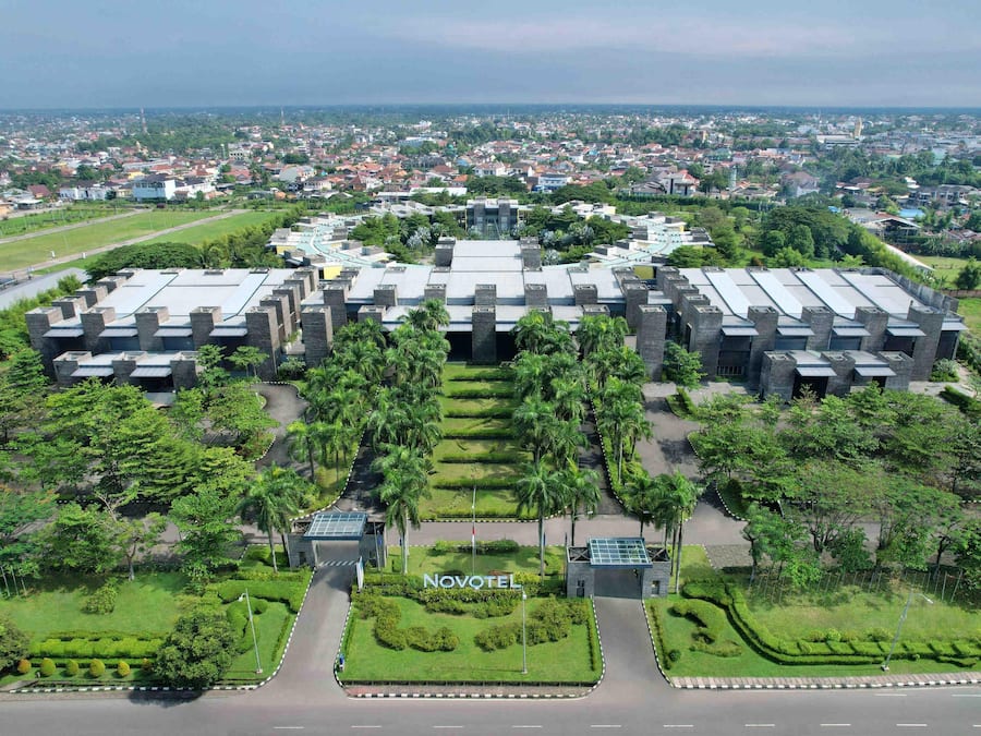 A Novotel hotel with a symmetrical design, multiple buildings, and a well-maintained garden.