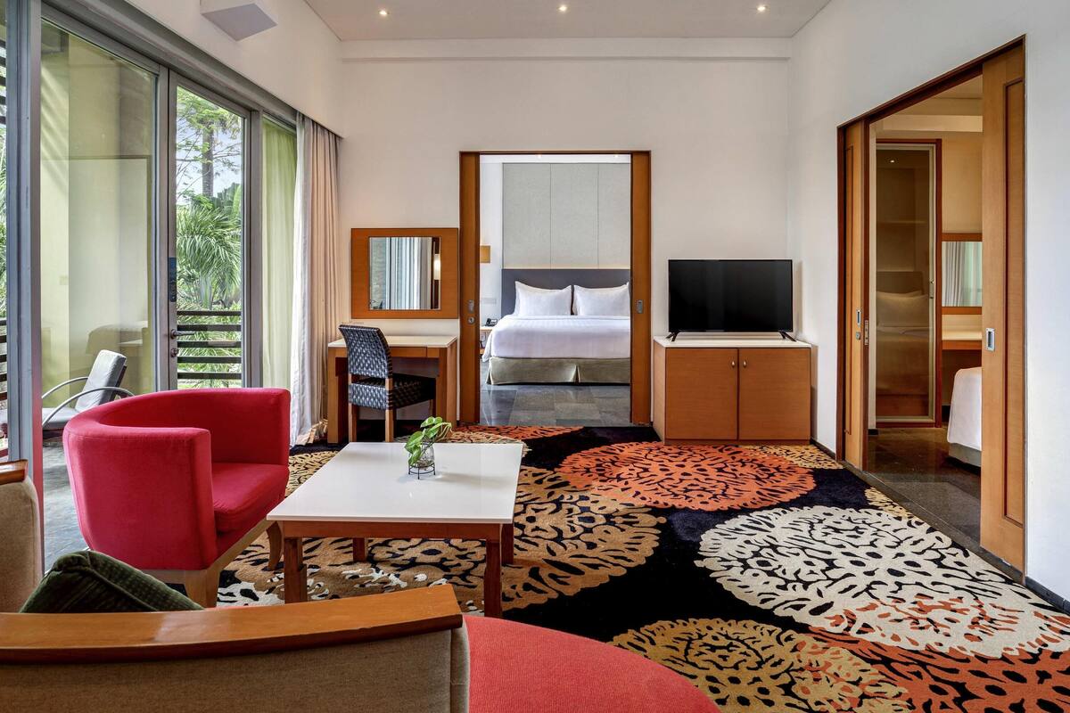 Een hotelkamer met een bed, een bureau met stoel, een televisie en een groot raam.