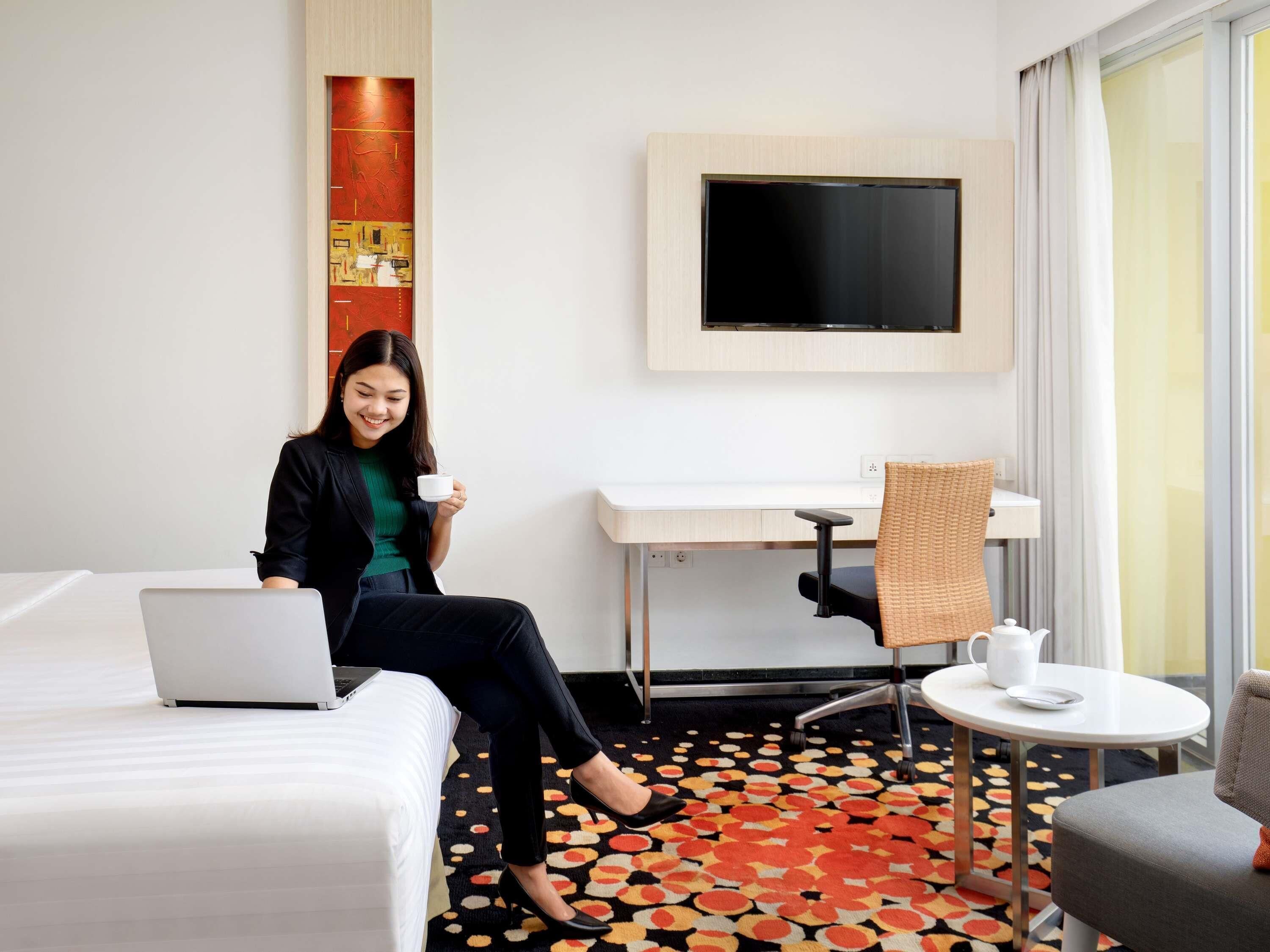 Une chambre d’hôtel avec un lit, un bureau, une télévision, une table basse et un sol à motifs.