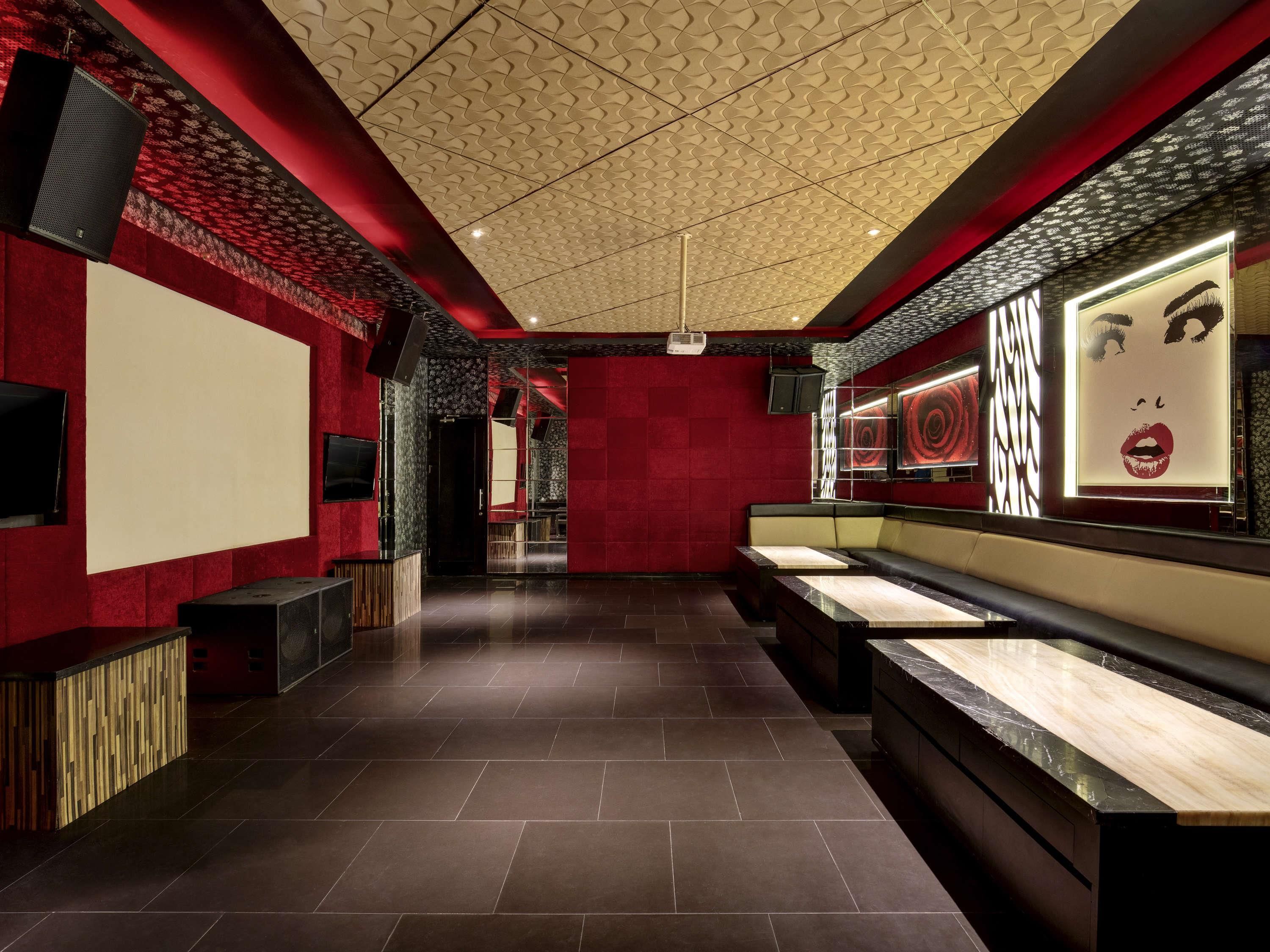 A modern interior with a red and black color scheme, a patterned ceiling, and a reception area with a counter and seating.