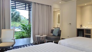 Een hotelkamer met twee bedden, een stoel, een tafeltje, een spiegel en uitzicht op groen.