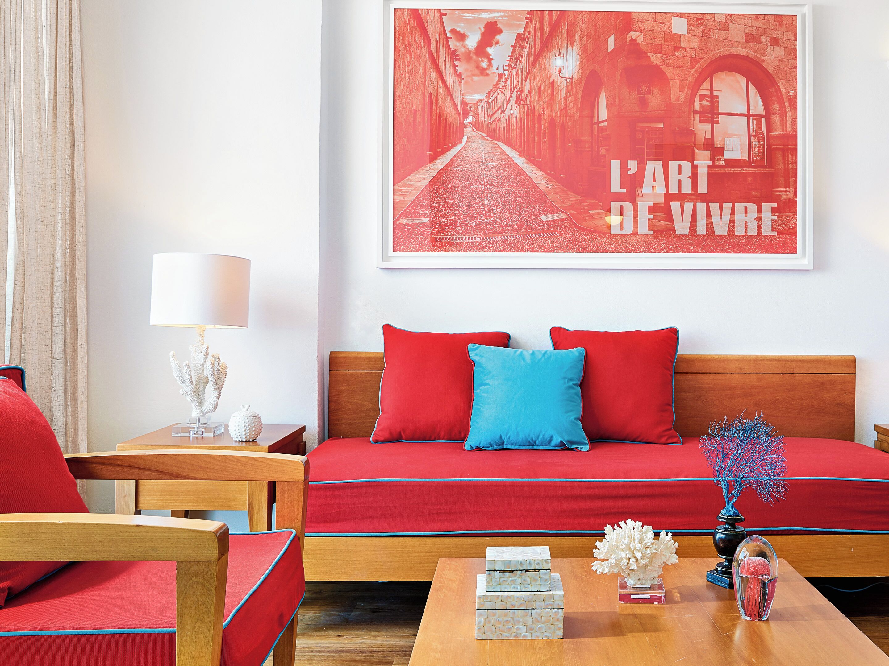 Una habitación con un sofá rojo, una mesa de centro de madera y un cuadro enmarcado en la pared.