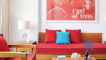 Una habitación con un sofá rojo, una mesa de centro de madera y un cuadro enmarcado en la pared.