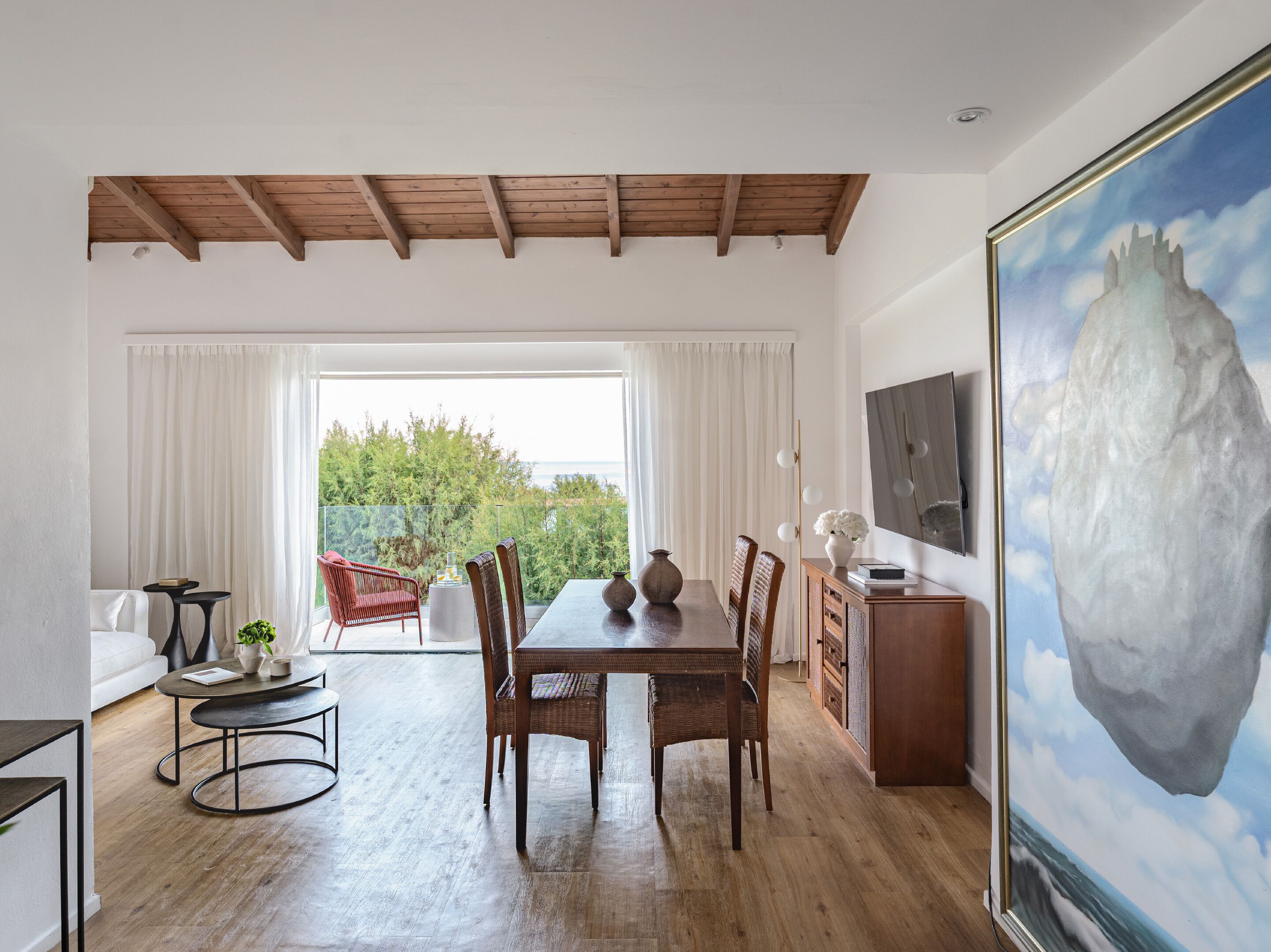 A dining area with a wooden table, chairs, and a view of the outdoors.