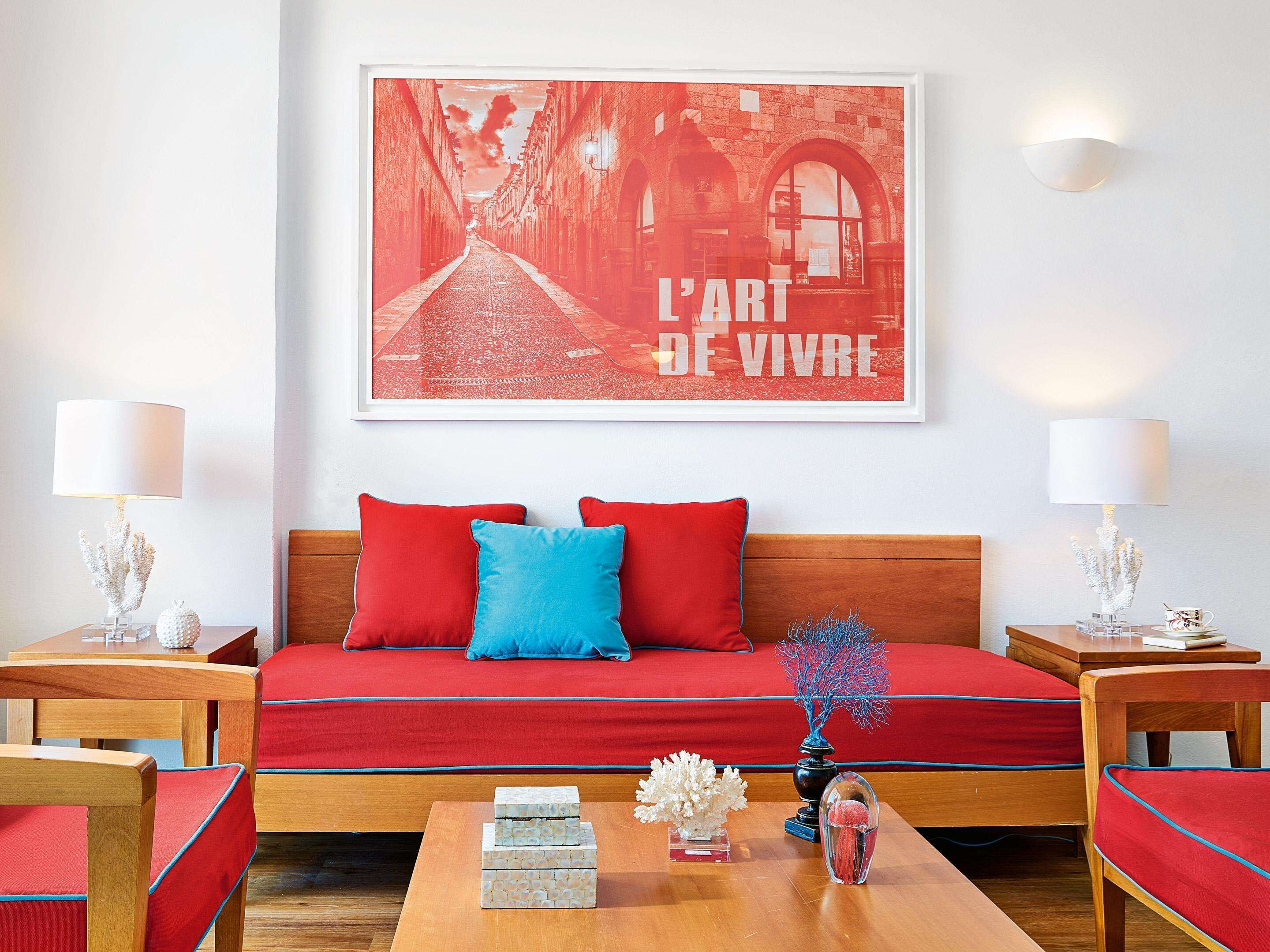 A room with a red sofa, two side tables with lamps, a coffee table with decorative items, and a framed poster on the wall.