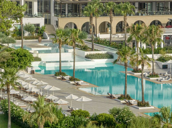 A resort with a large pool, palm trees, and lounge chairs. - Grecotel LUX ME Dama Dama (Rhodes)