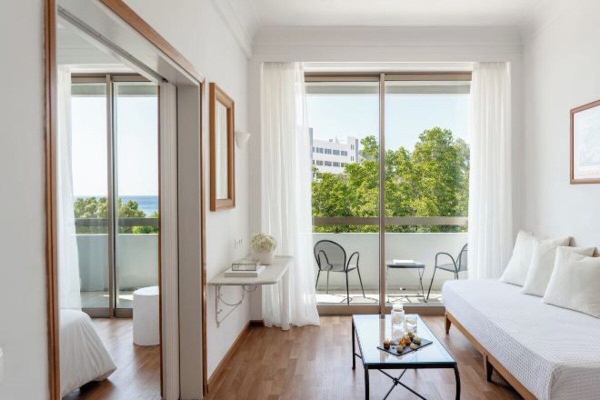 Una habitación de hotel moderna con balcón, una cama, una pequeña mesa y una silla.