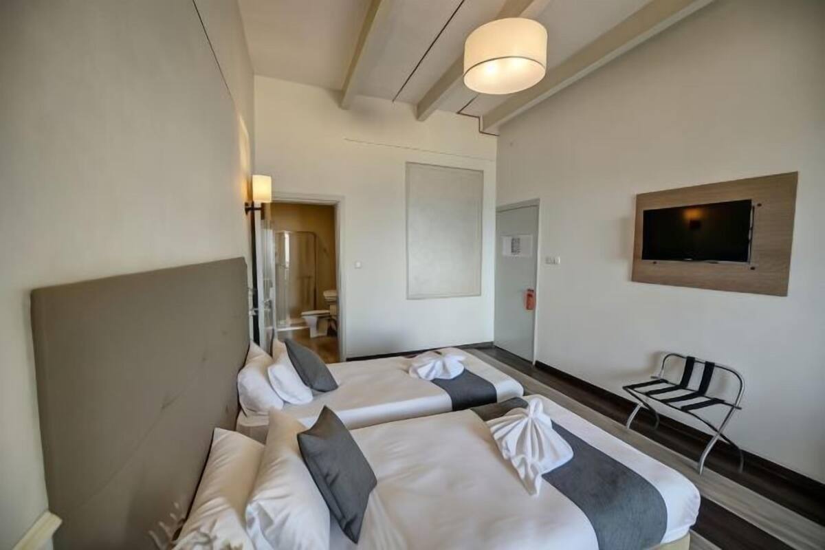 Ein Hotelzimmer mit zwei Betten, einem an der Wand befestigten Fernseher und einem Sessel.