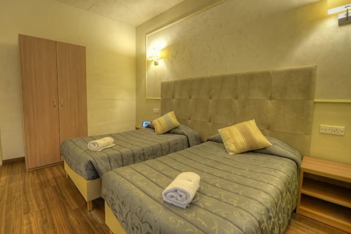Ett hotellrum med två sängar, en garderob och ett nattduksbord.