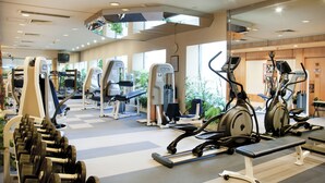 Un gimnasio con diversos equipos de ejercicio, incluyendo cintas de correr, elípticas y máquinas de pesas.
