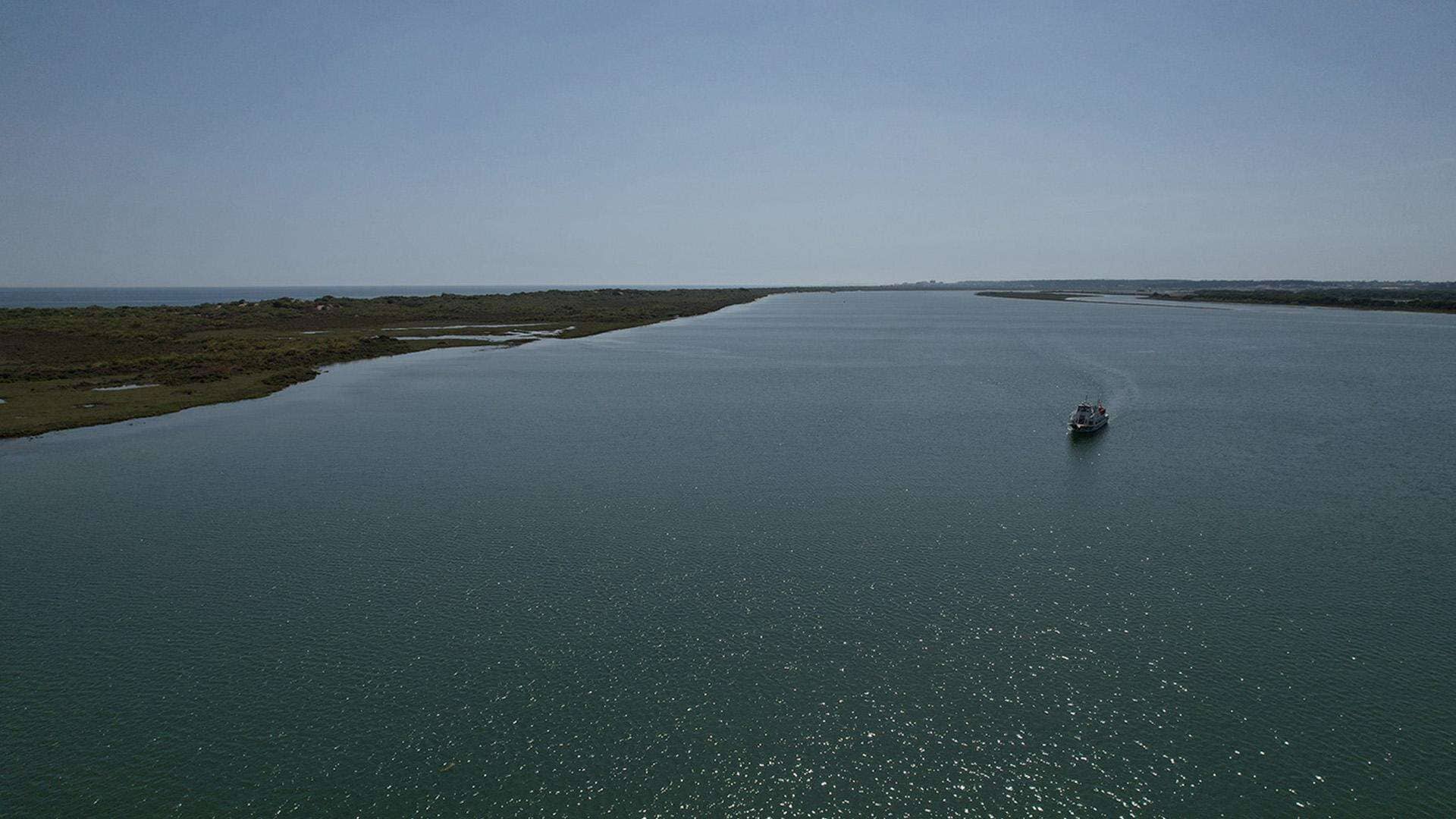 A boat on a calm body of water with a clear sky.