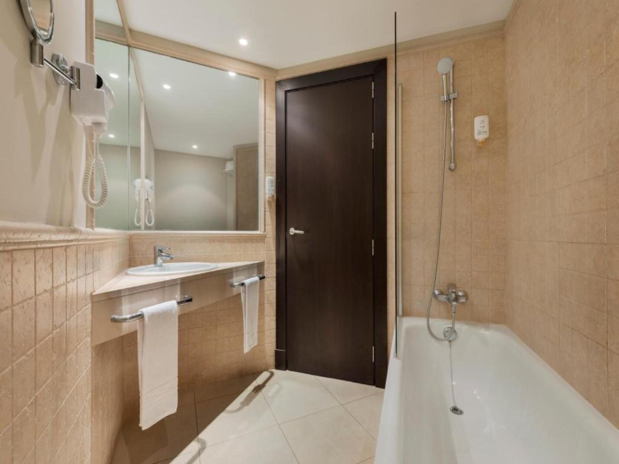 Un bany amb banyera, un lavabo, un mirall i una porta.