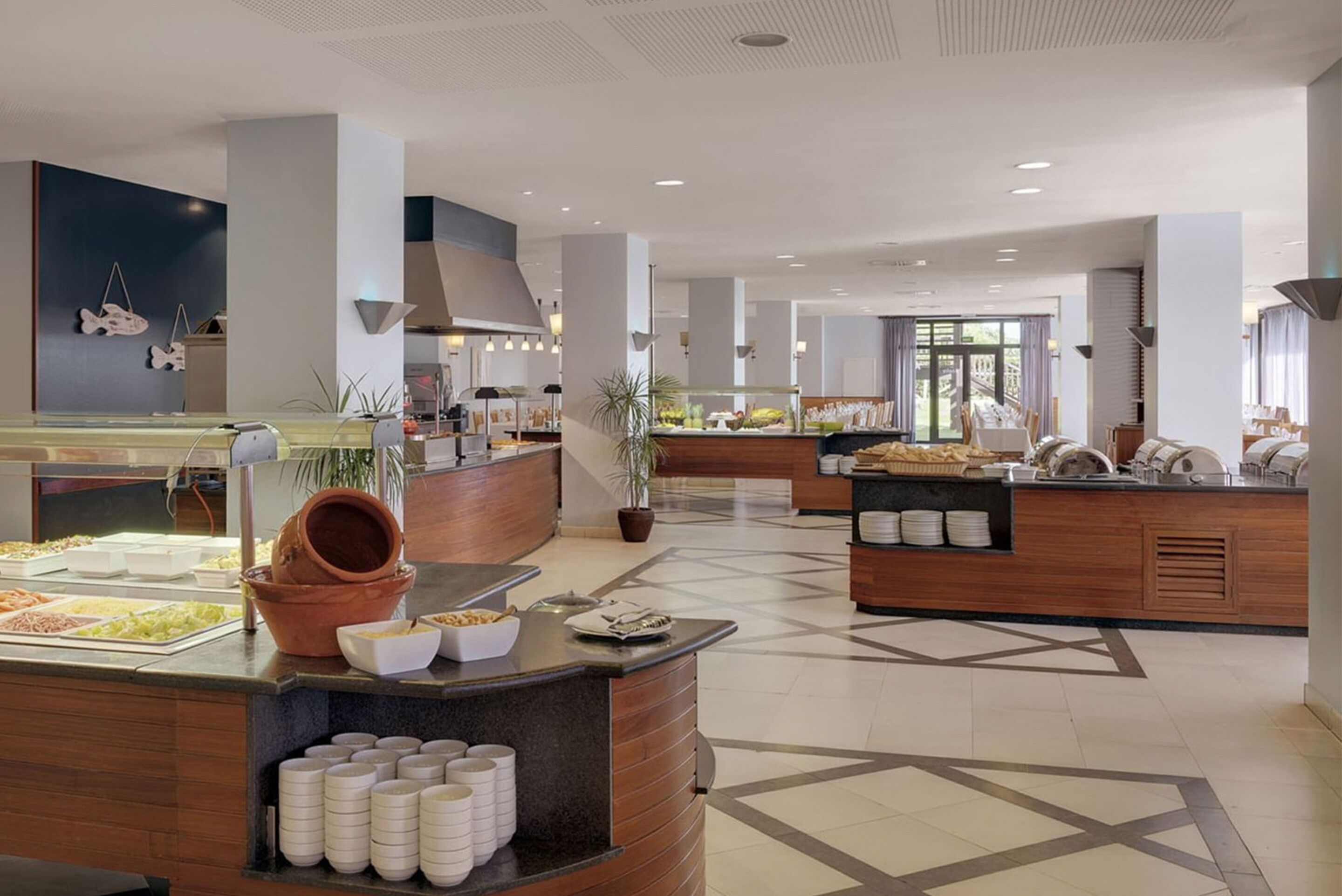 A modern hotel lobby with a buffet area, a reception desk, and a staircase leading to the upper floors.