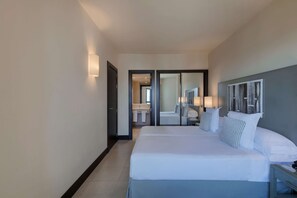 A hotel room with a large bed, a nightstand, a mirror, and a view into the bathroom. - Precise Resort El Rompido - The Club (Cartaya)