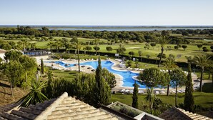 A resort with a swimming pool, lounge chairs, and a view of the surrounding landscape.
