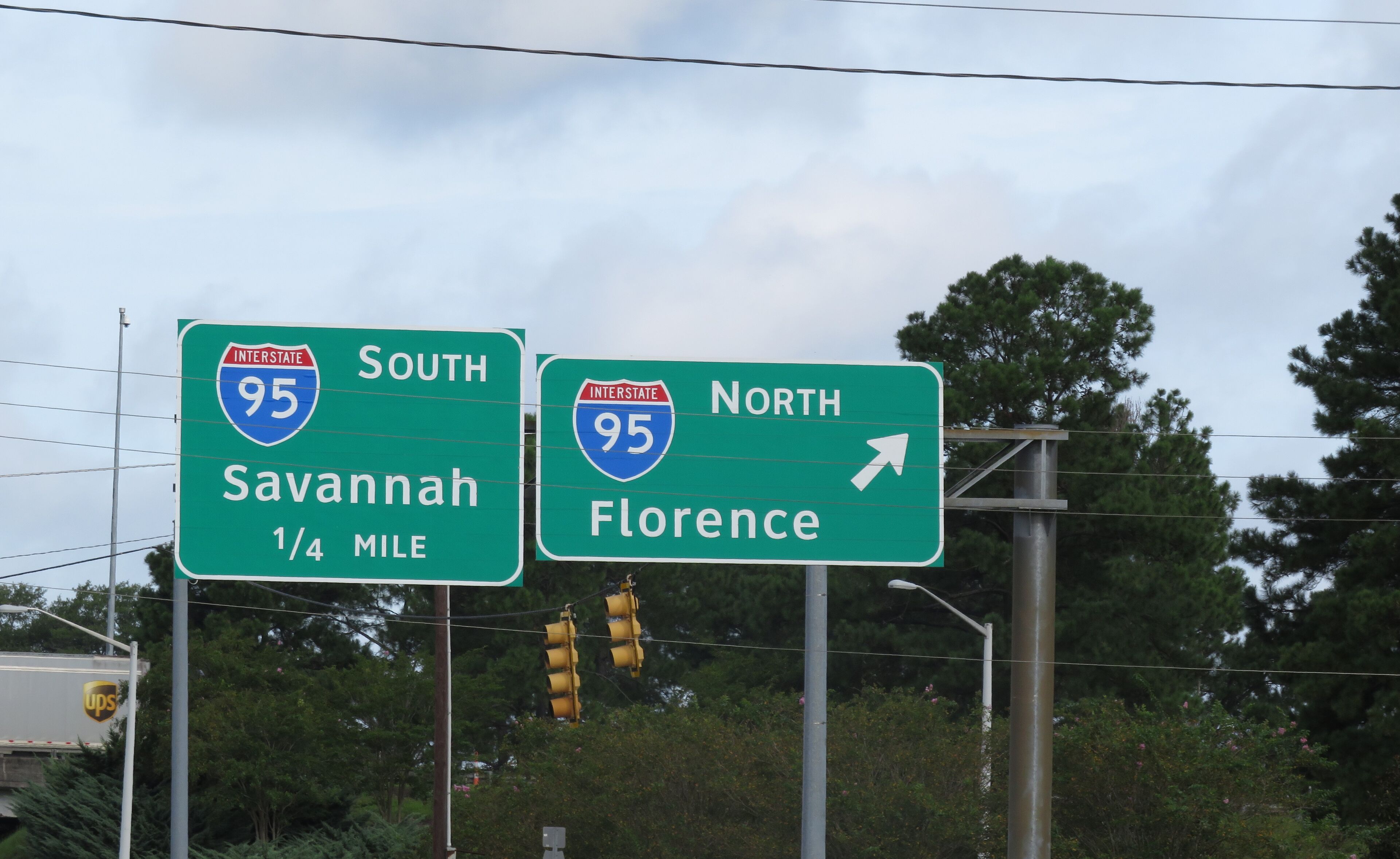 Deux panneaux verts placés le long de l’autoroute indiquant les directions à suivre pour rejoindre l’Interstate 95, en direction du sud vers Savannah et en direction du nord vers Florence.