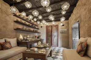 A cozy interior with a checkered floor, a wooden table set with tea, and shelves with pottery and decorative items.