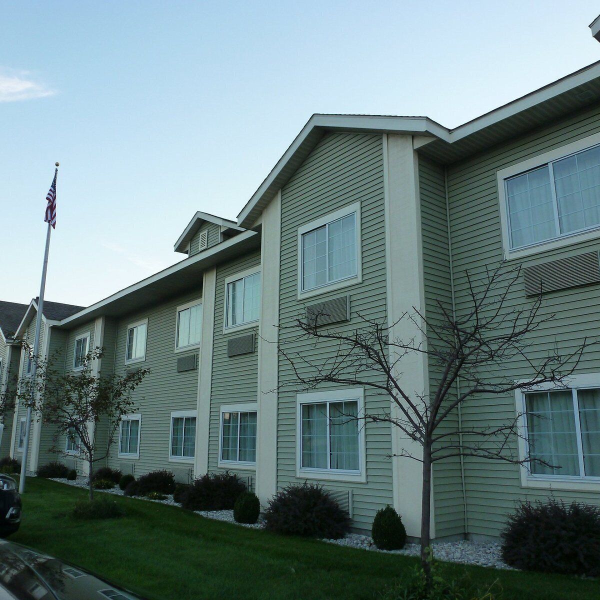 A multi-story residential building with a flat roof, multiple windows, and a flagpole.