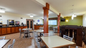 A restaurant with multiple dining tables and chairs, a counter with a coffee machine, and a television mounted on the wall. - Baymont by Wyndham Beulah (Beulah)