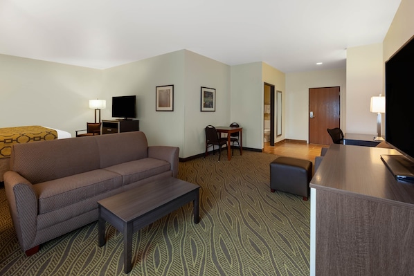 Habitación de hotel con sofá, una mesita, televisor, escritorio y silla.