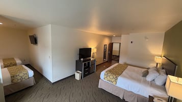 A hotel room with two beds, a TV, a desk, and a mirror.