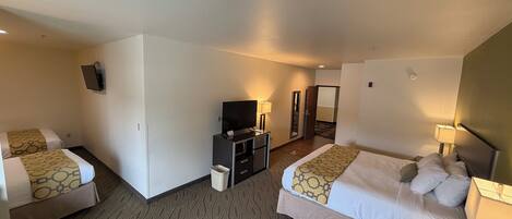 Une chambre d’hôtel avec deux lits, une télévision, un bureau et un miroir.