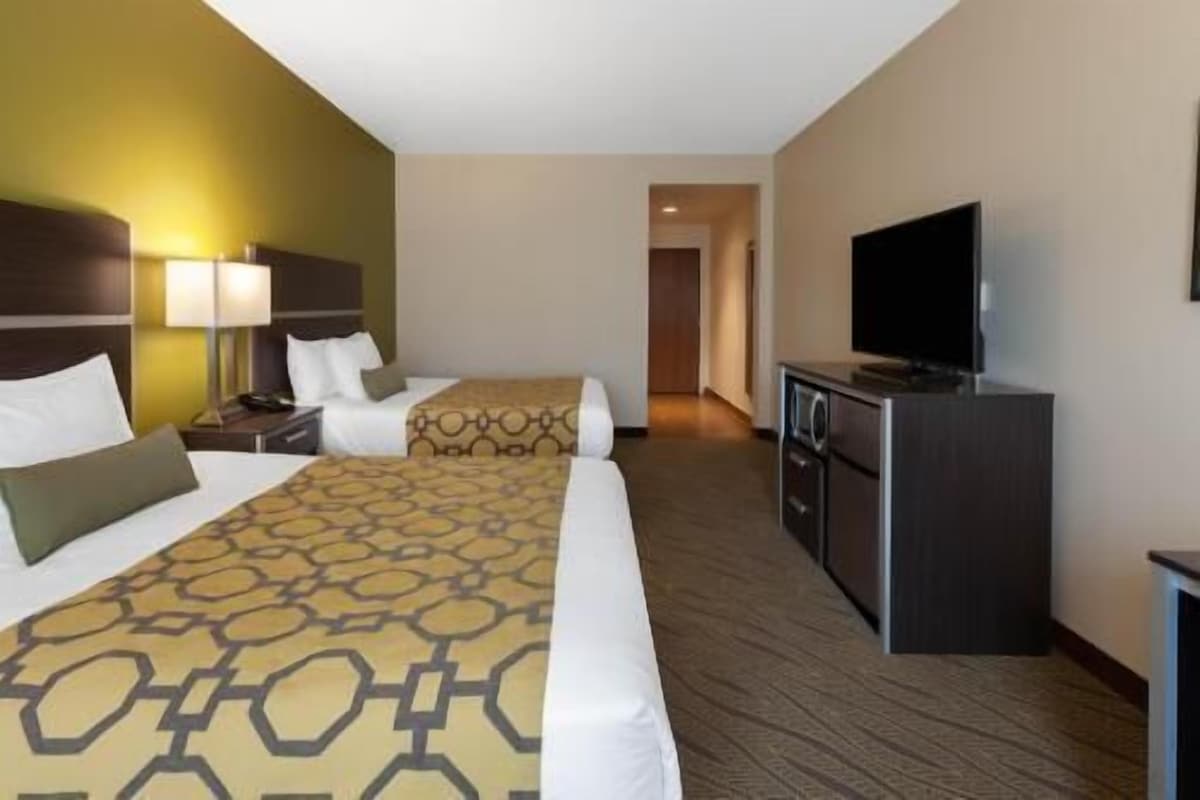 Habitación de hotel con dos camas, televisión, escritorio y lámpara.