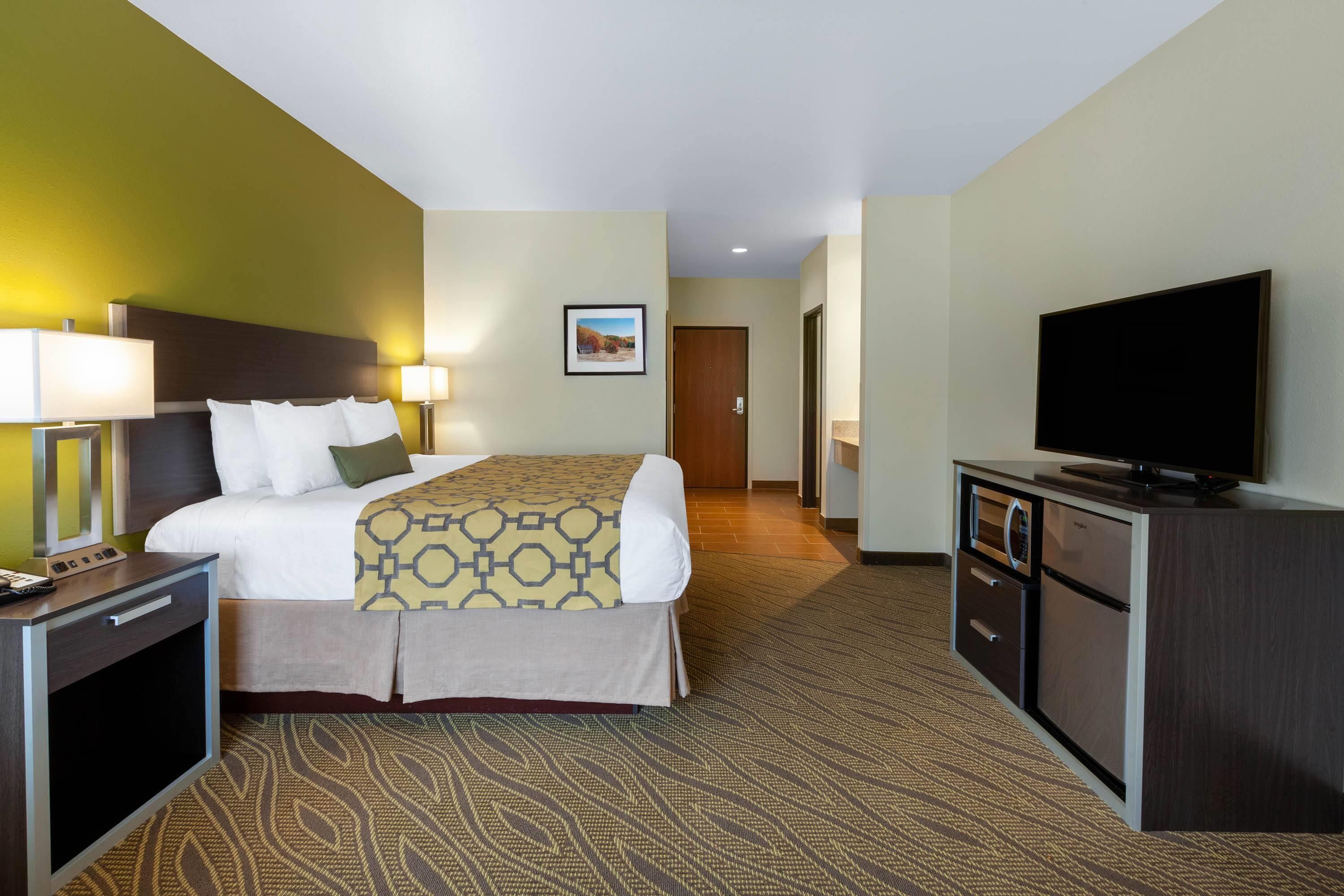 A hotel room with a bed, bedside tables, a television, and a desk.