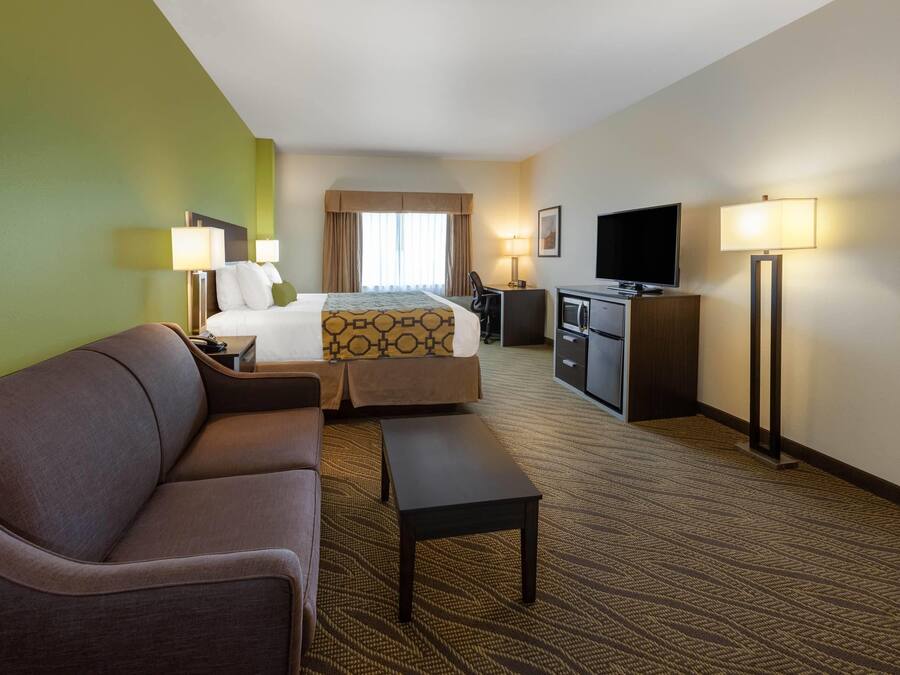 A hotel room with a bed, a sofa, a desk, a television, and a lamp.