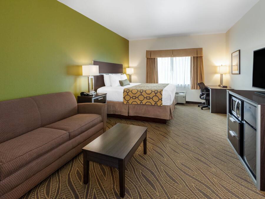 A hotel room with a bed, a sofa, a desk, a television, and a minibar.
