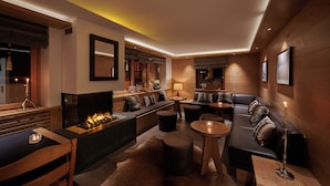 A modern lounge area with a fireplace, seating, and a bar. - Hotel Ambiance  (Zermatt)