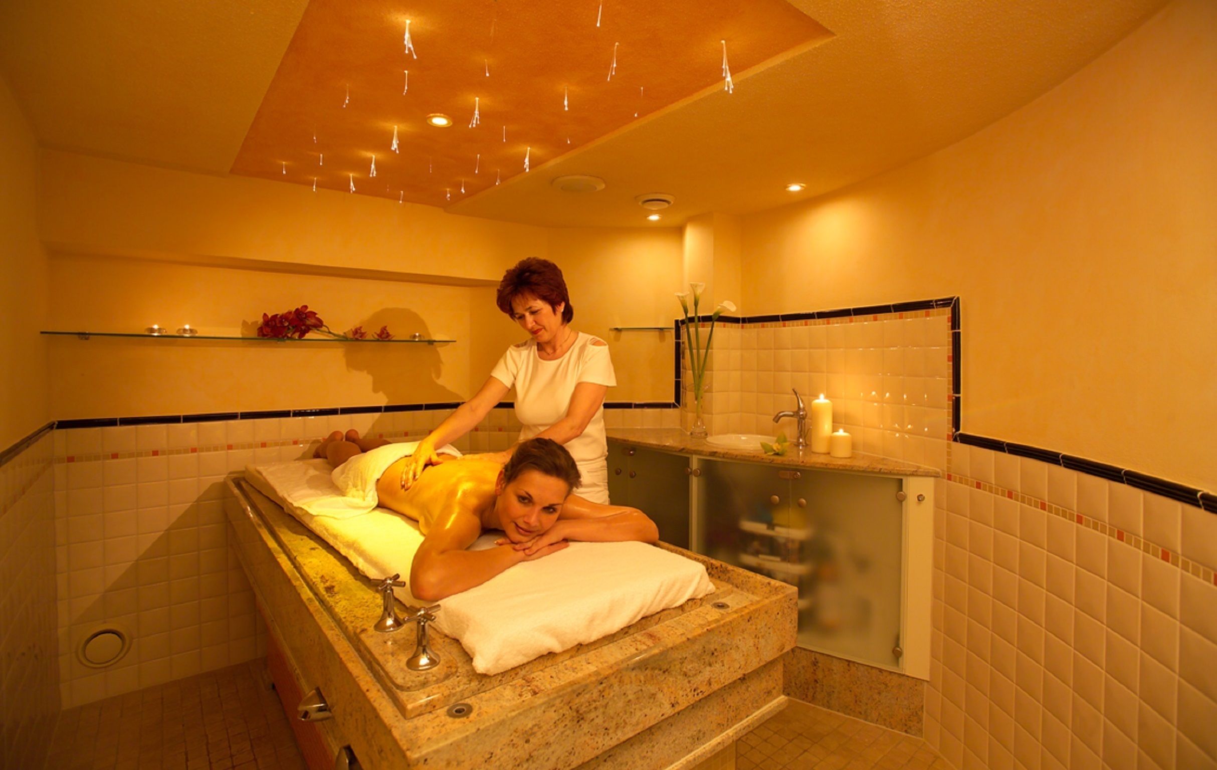Ein Spa-Raum mit Massagetisch, Waschbecken und Spiegel.