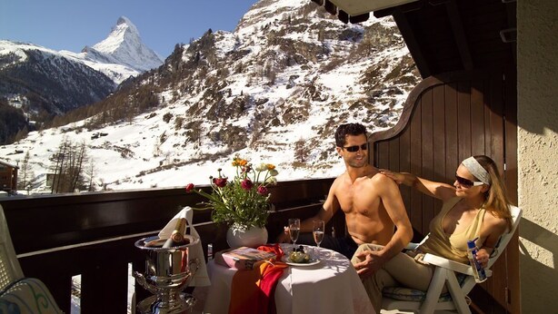 A couple dining on a balcony with a mountain view.