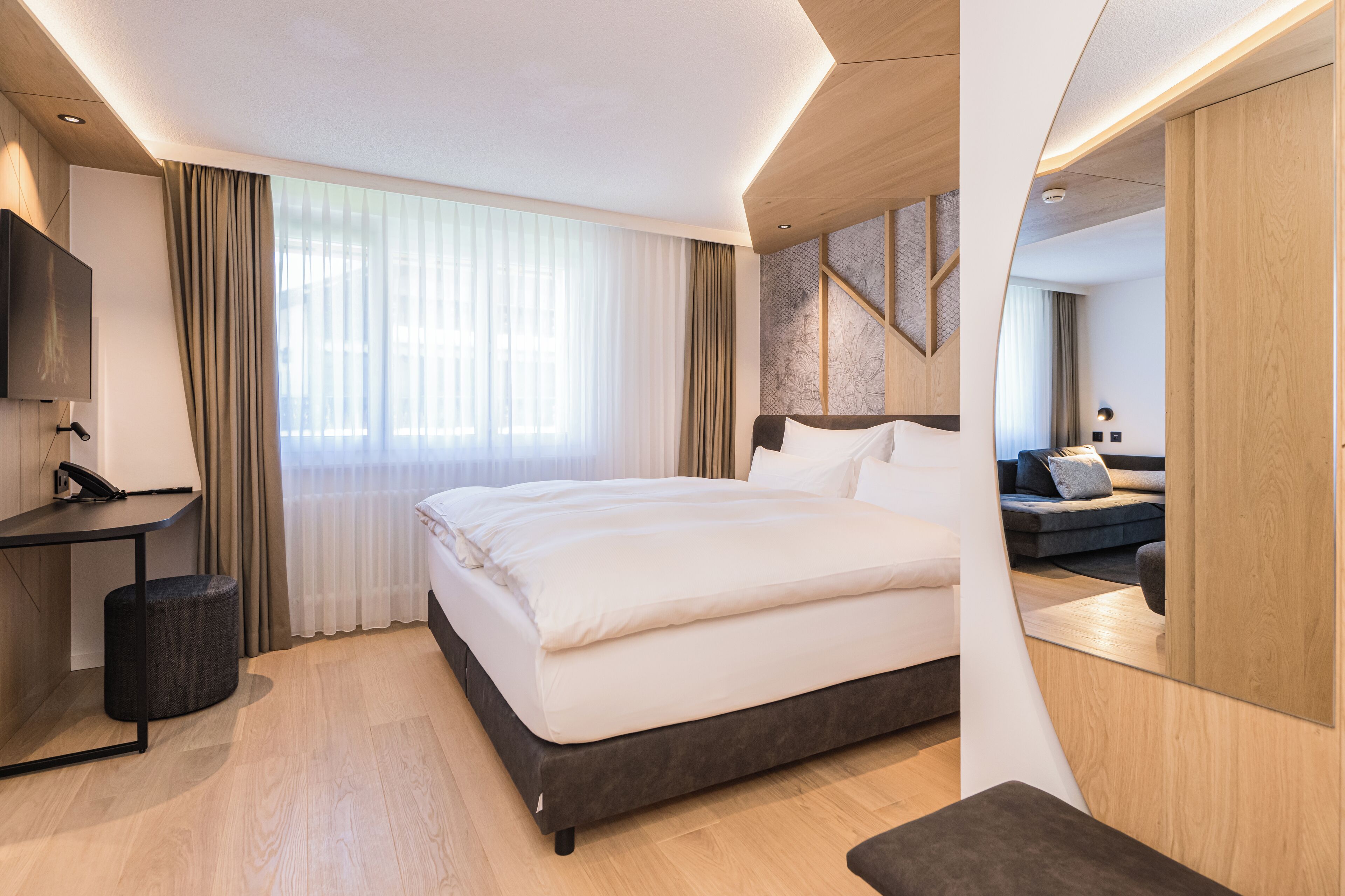 A modern hotel room with a large bed, a desk, and a TV.