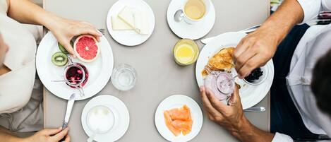 A dining table with plates of food, including salmon, grapefruit, and other items.