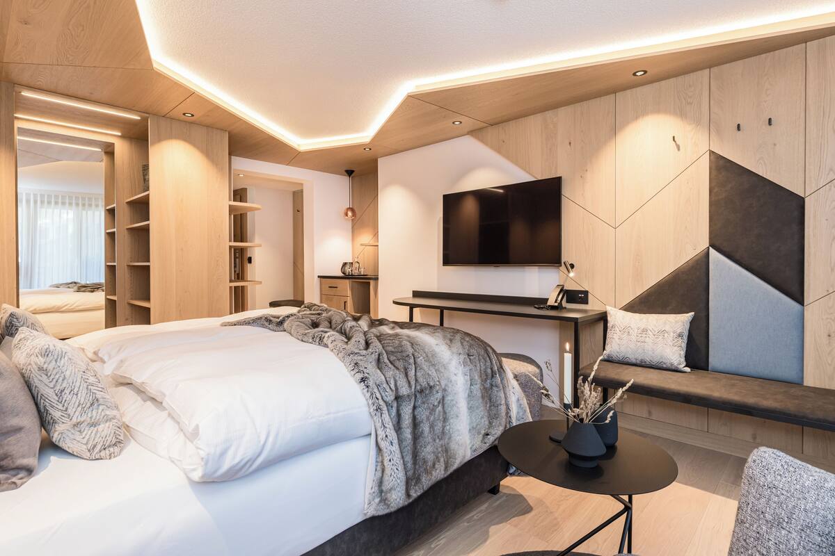 A modern hotel room with a large bed, a desk, a flat-screen TV, and a seating area.