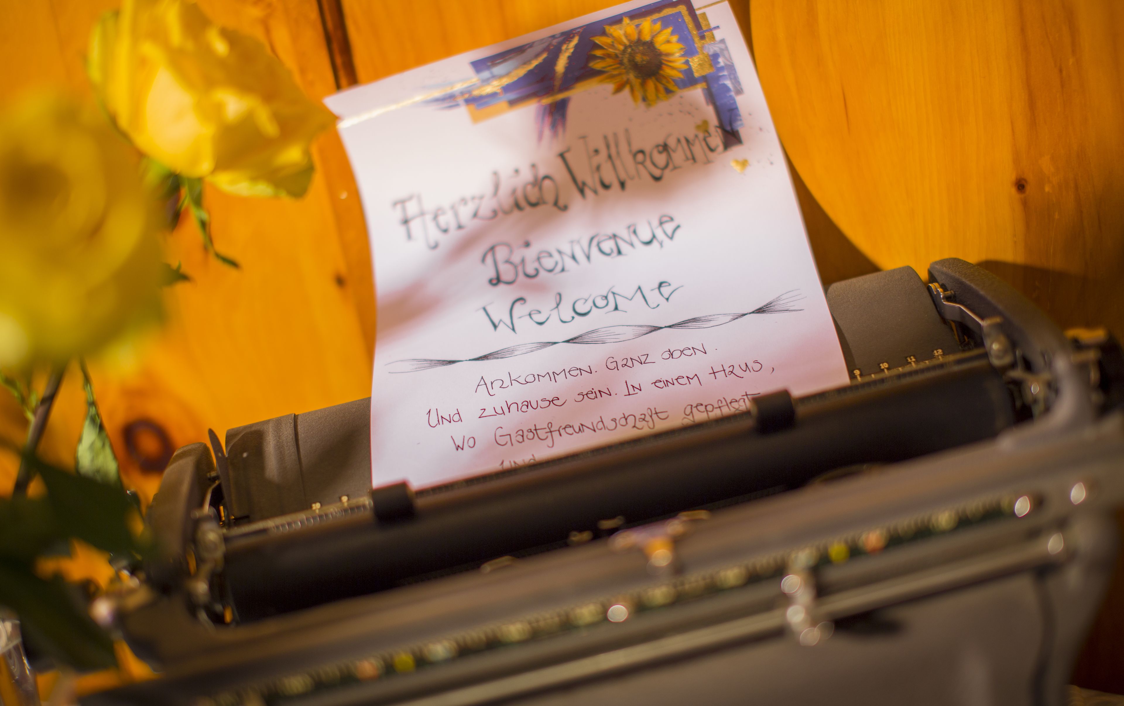 A typewriter with a handwritten welcome note in German.