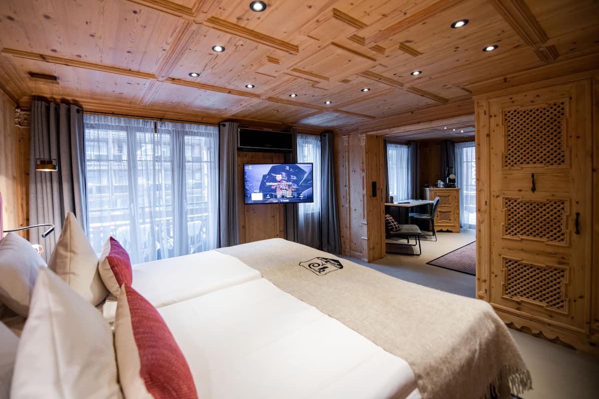 A hotel room with a large bed, a television, and a dining area with a table and chairs.