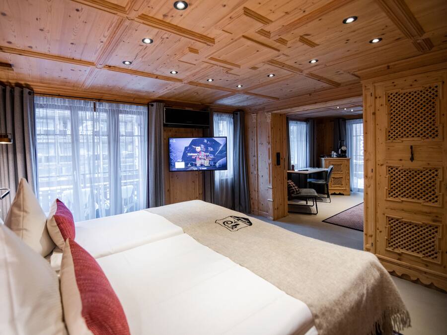 Ein Hotelzimmer mit einem großen Bett, einem Fernseher und einem Essbereich mit Tisch und Stühlen.