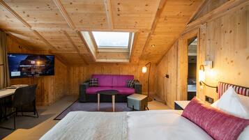 A cozy room with a bed, a sofa, a small table, and a television displaying a welcome message.