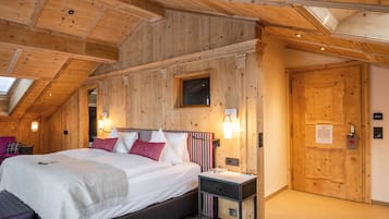 Una camera da letto con soffitto in legno, un letto con biancheria da letto bianca, un comodino e una finestra.