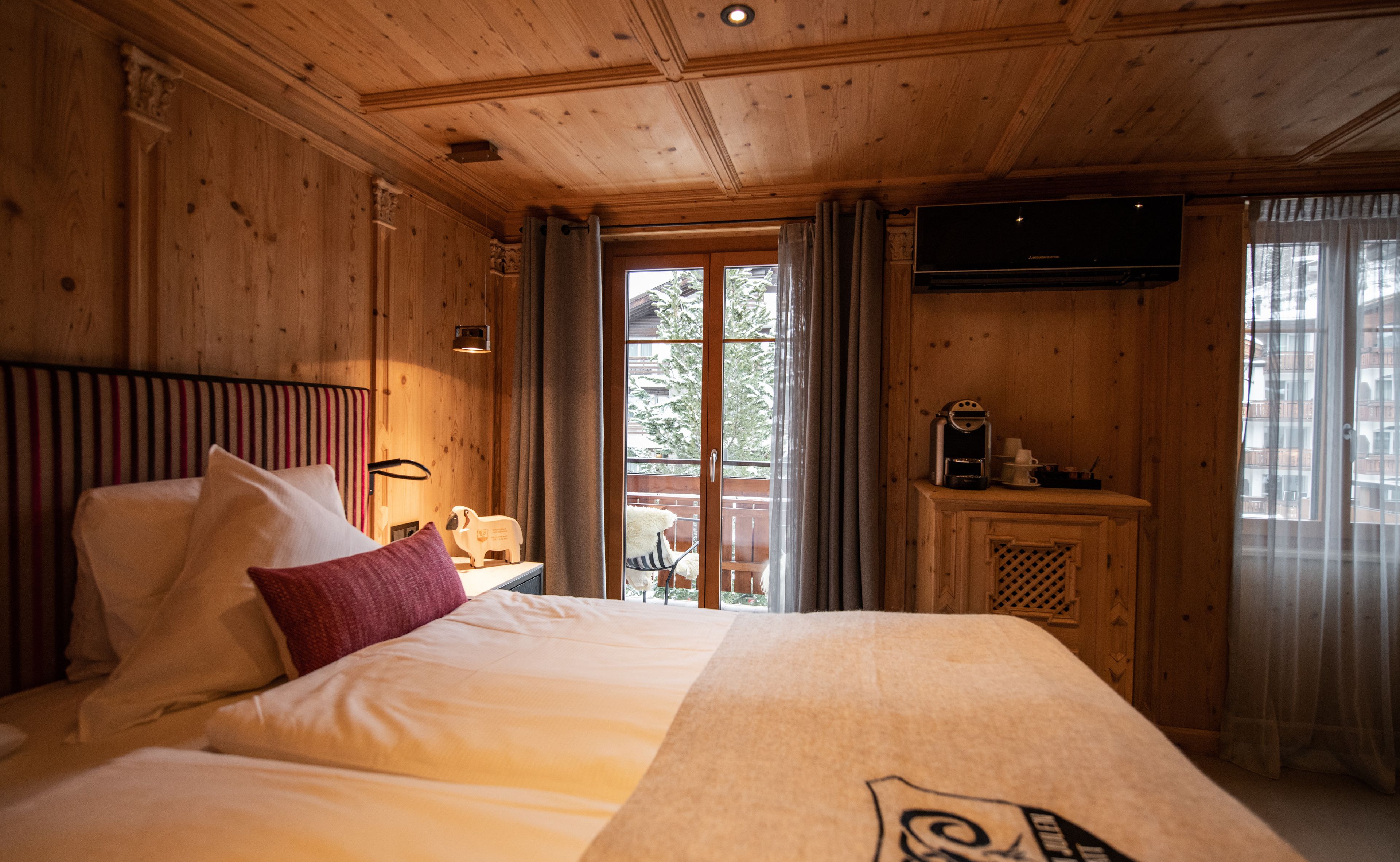 Habitación de cabaña de madera con una cama, una mesita de noche, una lámpara, una cafetera y un televisor.