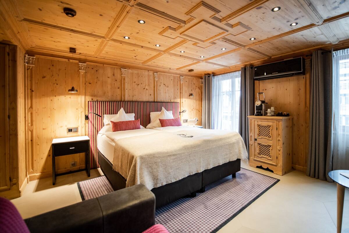 A wooden-paneled bedroom with a large bed, a TV, and a small table.