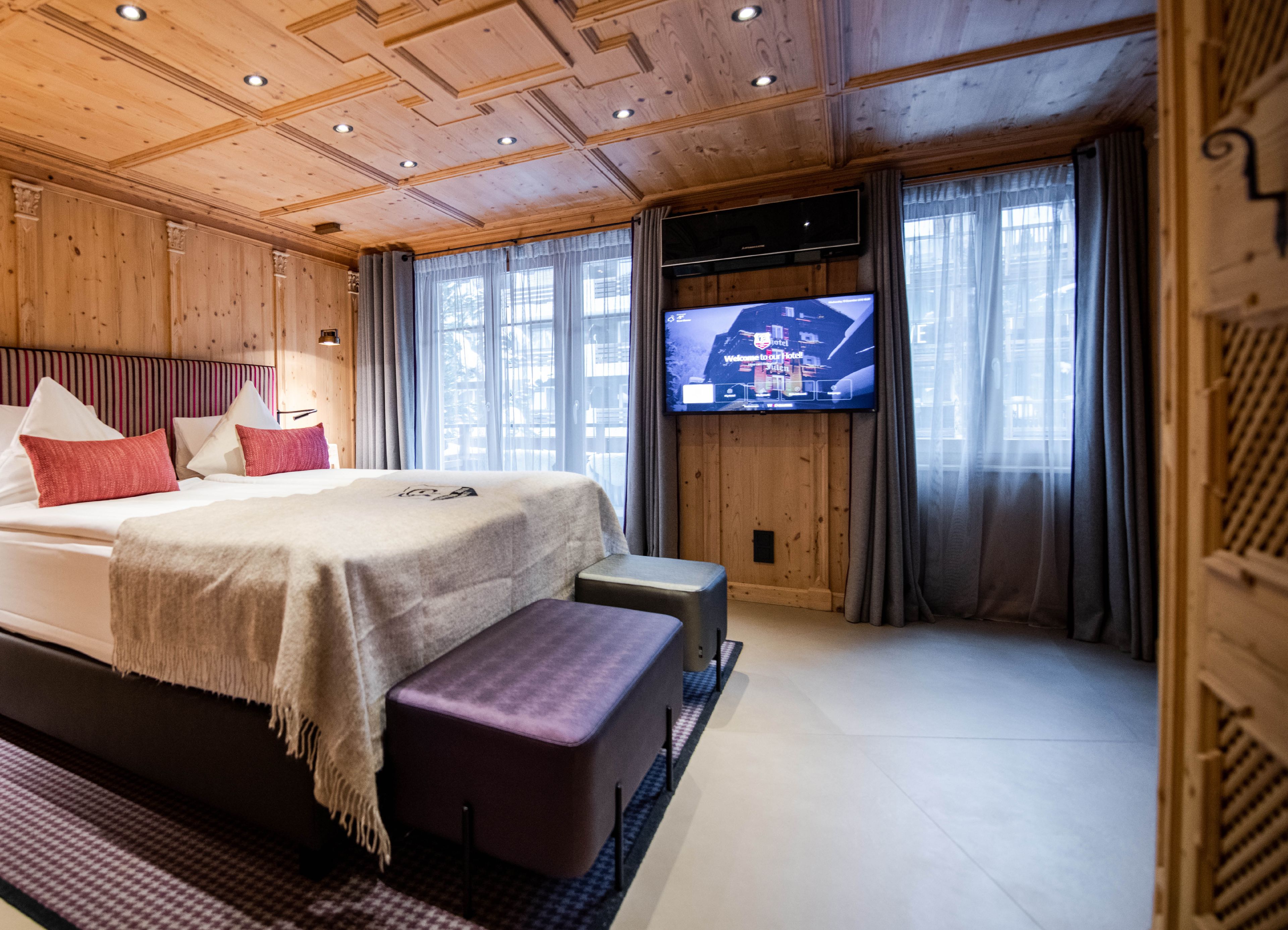 Habitación de hotel con una cama grande, un televisor de pantalla plana en la pared y techo de madera.