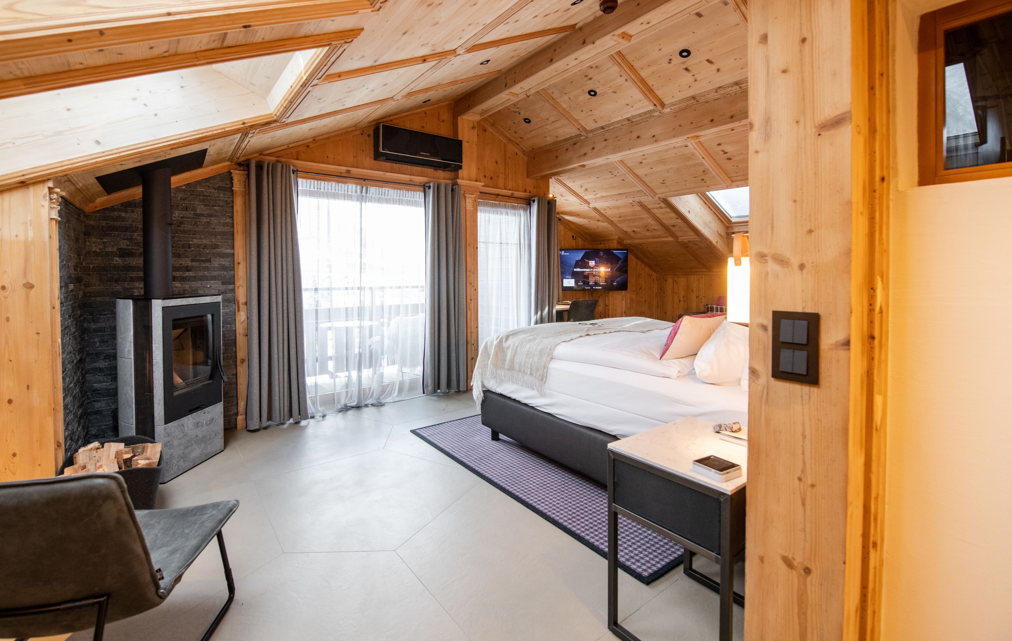Une pièce chaleureuse, aménagée dans un chalet en bois, avec un lit, une télévision, une cheminée et un bureau.
