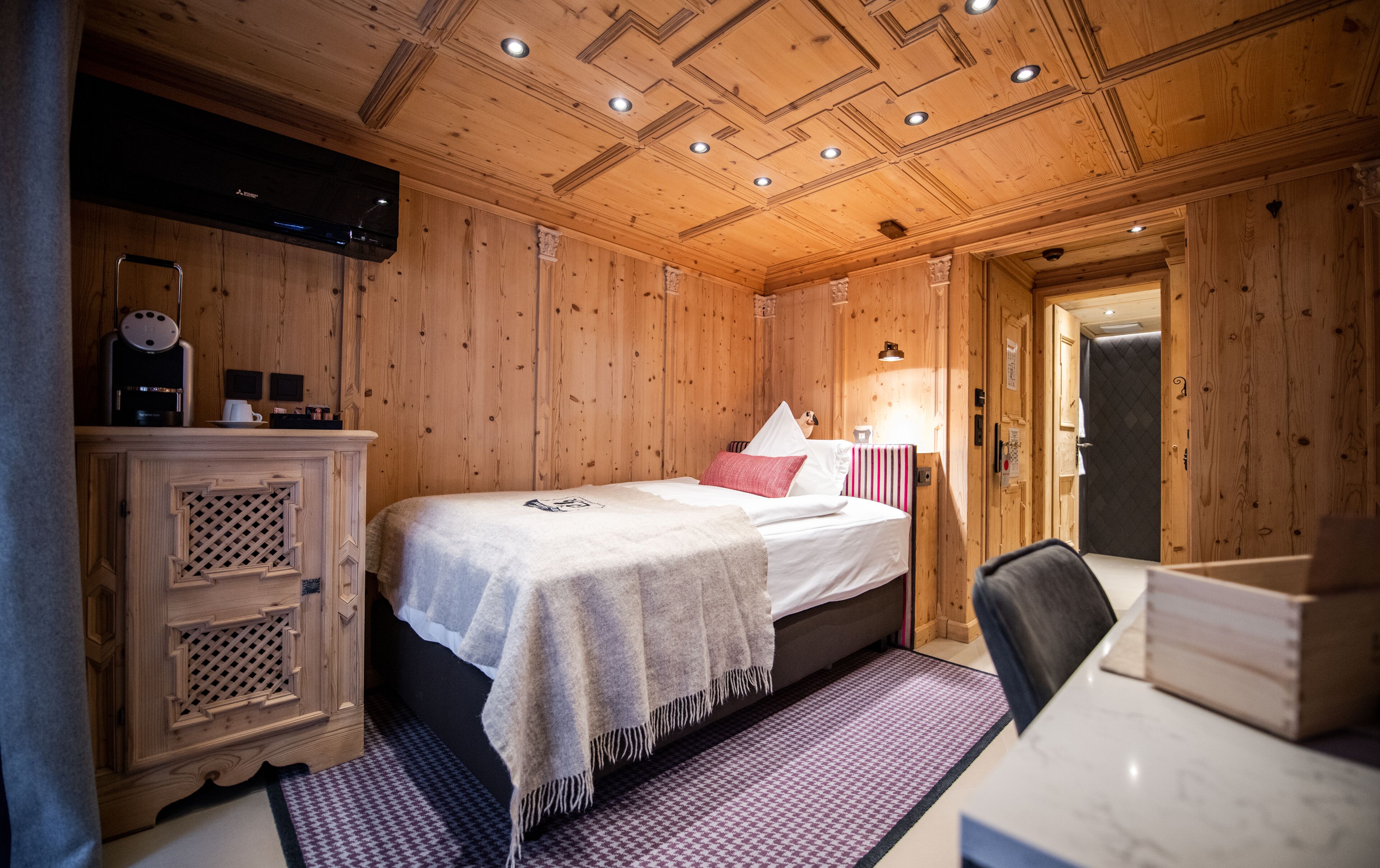A wooden room with a bed, a desk, and a cabinet.