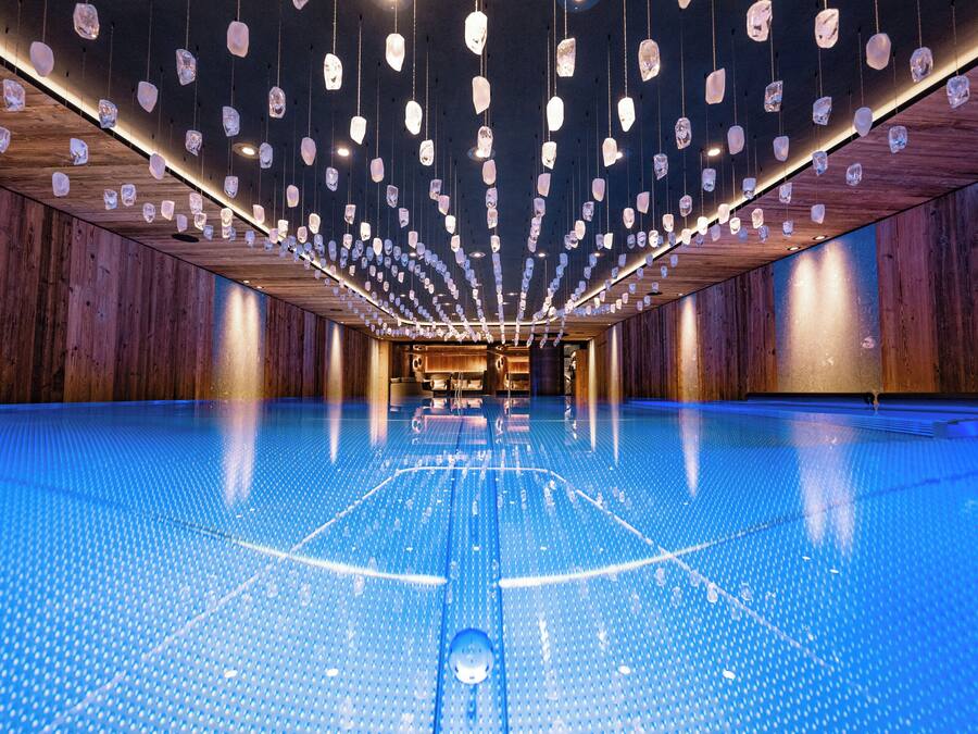 A spacious indoor area with a polished blue floor and hanging crystal-like lights.