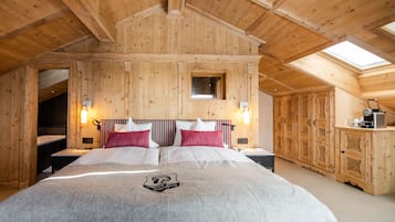 Una habitación de madera con una cama, un ventanal pequeño y una escalera.