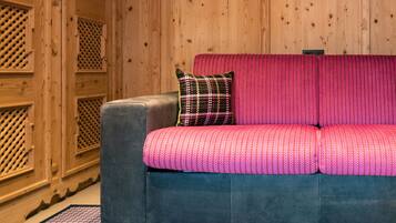 Una habitación con un sofá gris y un cojín estampado rosa.